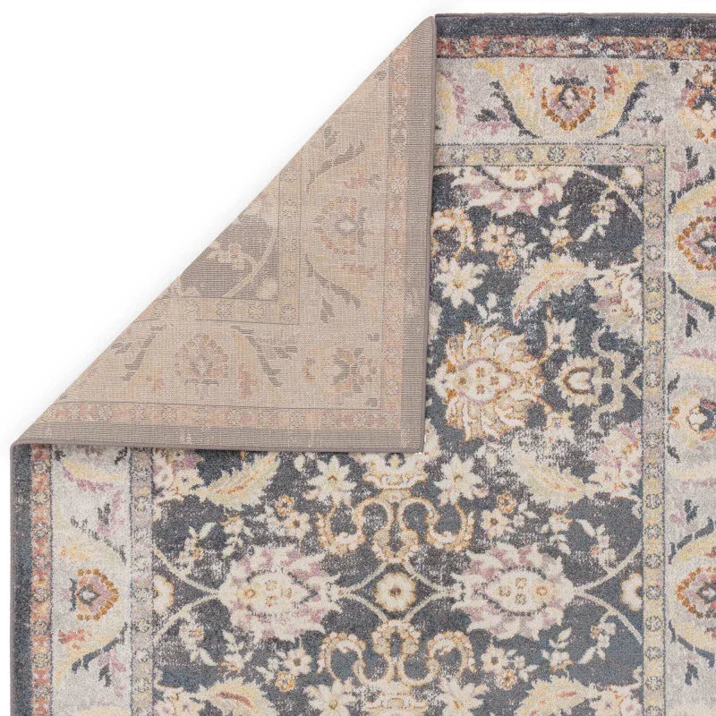 Traditional floral area rug with grey, cream, and gold pattern, corner flipped to show backing