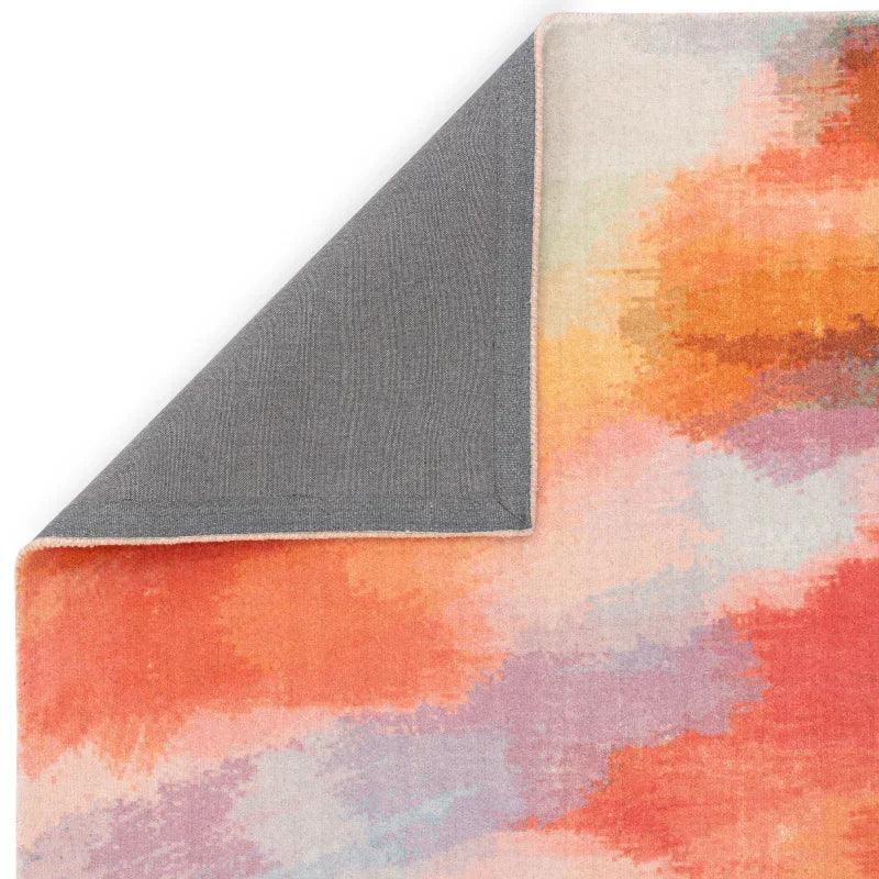 Abstract multicolor area rug with orange, pink, and purple pattern, corner flipped to show backing