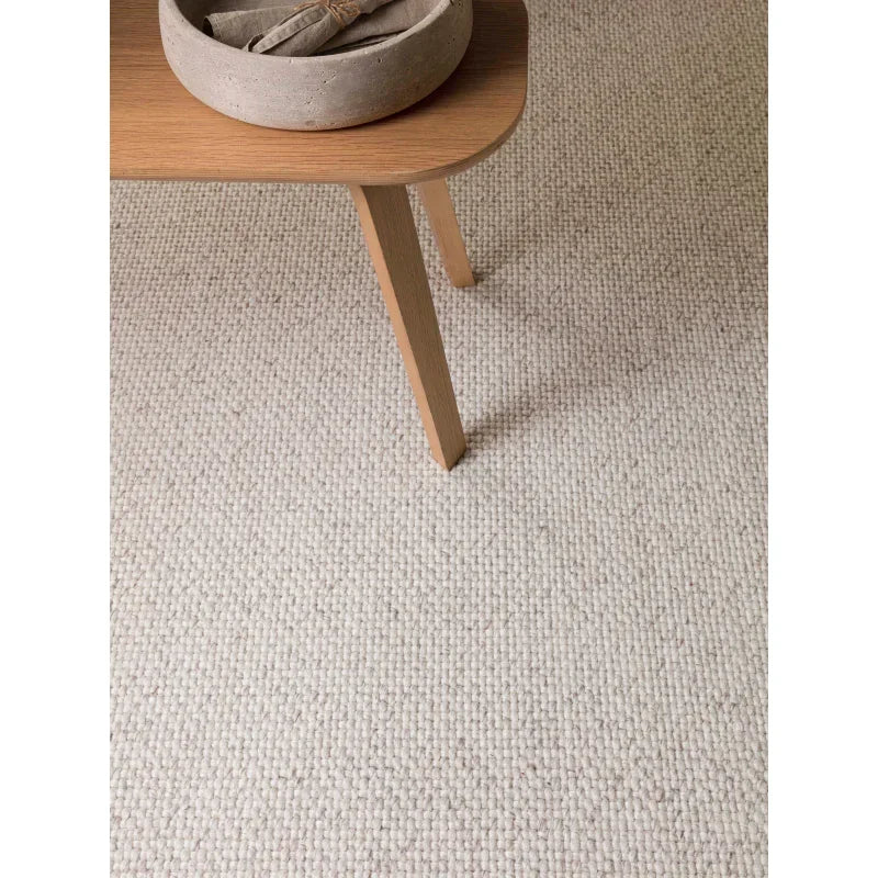 Natural wool loop pile carpet with wooden table and decorative bowl