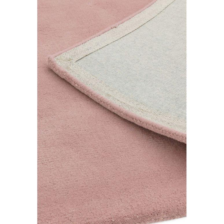 Close up of pink area rug with soft texture and detailed stitched edging