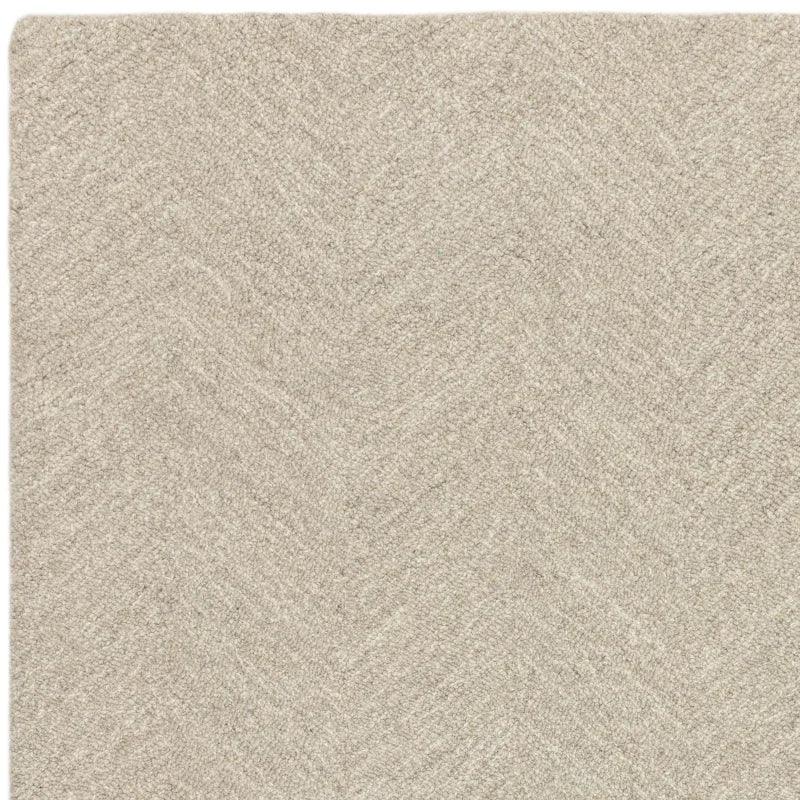 Beige textured wool rug with subtle chevron pattern, close-up corner view