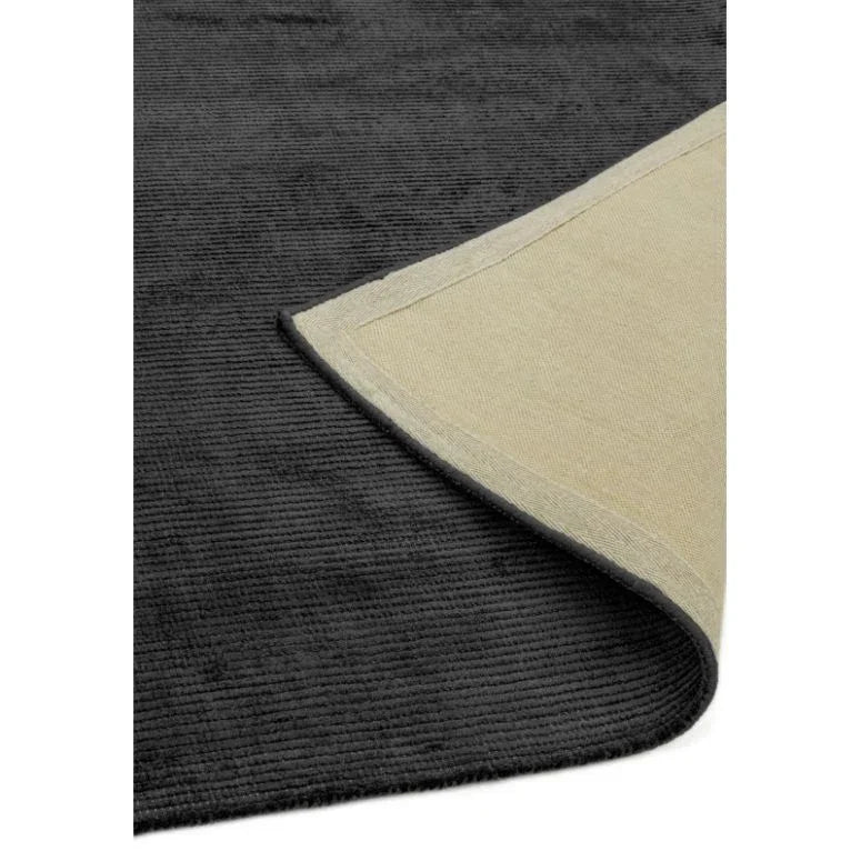 Charcoal grey area rug with textured surface and corner folded to show backing