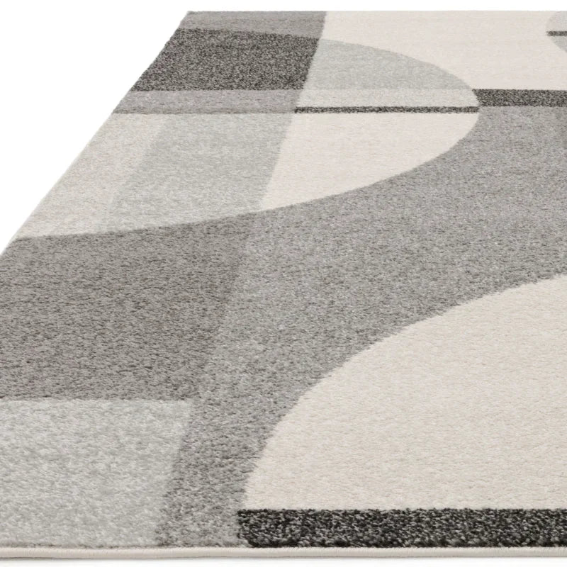 Grey geometric rug with modern pattern and soft pile, shown from a side angle