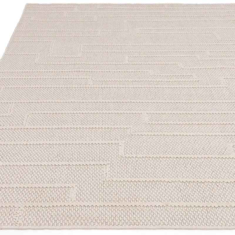 Beige textured rug with geometric pattern, close-up view of woven fabric and raised lines