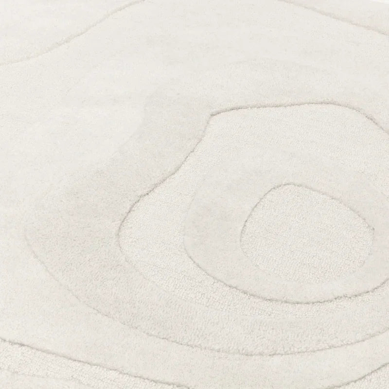 Textured cream area rug with raised abstract swirl pattern detail