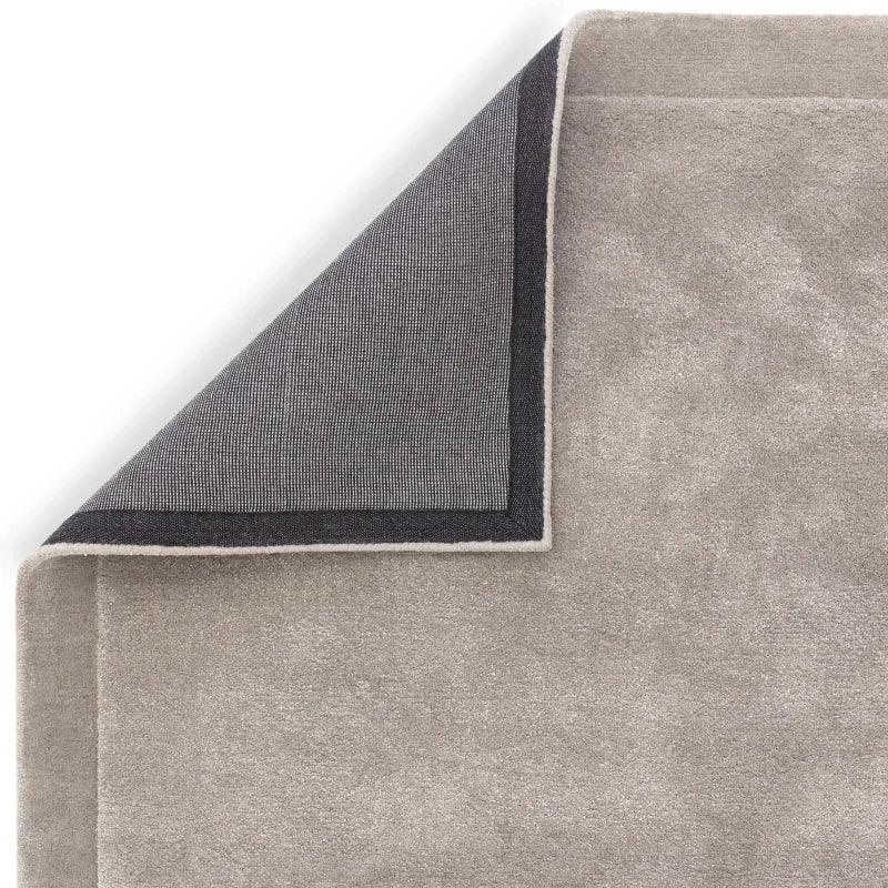 Close-up of folded beige rug corner showing pile and grey backing