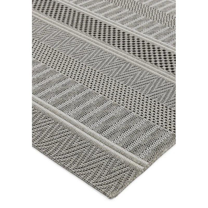 Grey patterned area rug with textured woven stripes and geometric designs, angled corner view