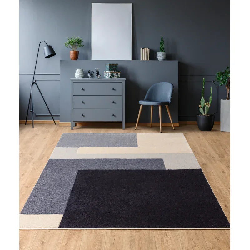 Geometric area rug with grey, cream, and black blocks on wooden floor in modern living room