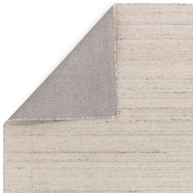 Neutral woven area rug corner folded to show backing texture