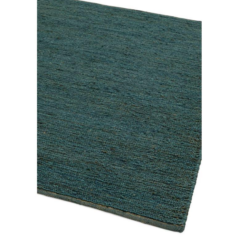Teal woven area rug with textured surface, corner detail shown on white background
