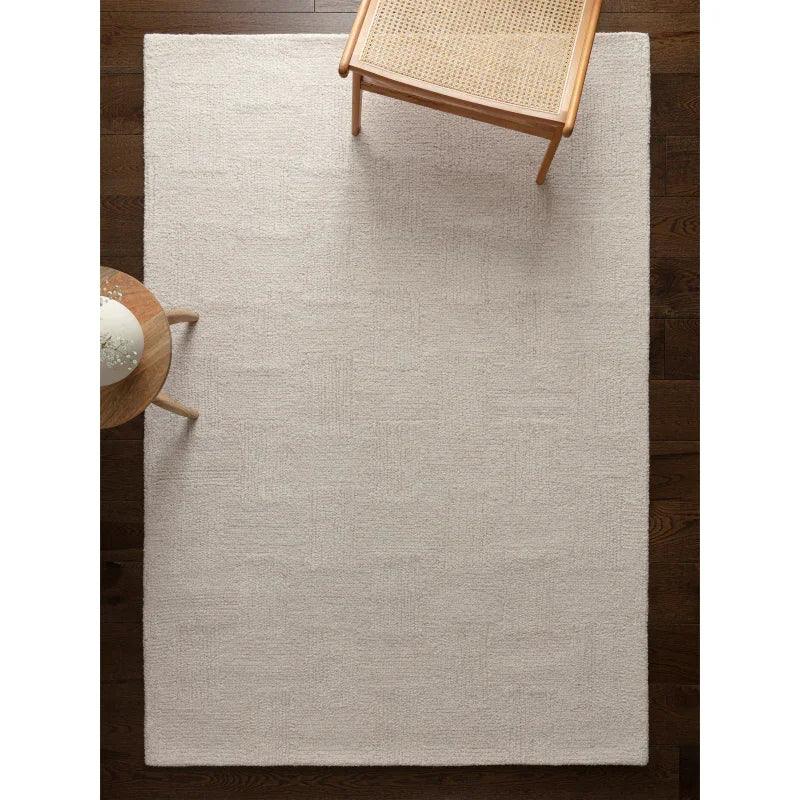 Cream textured area rug on dark wood floor with wooden chair and small round table