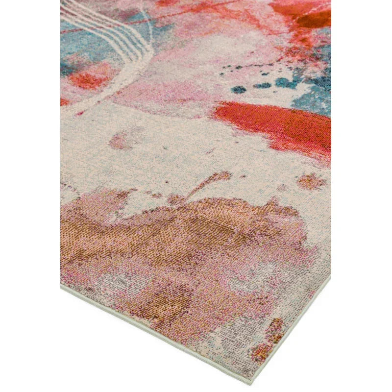Abstract area rug with pink, red, blue and cream blended pattern, close corner view