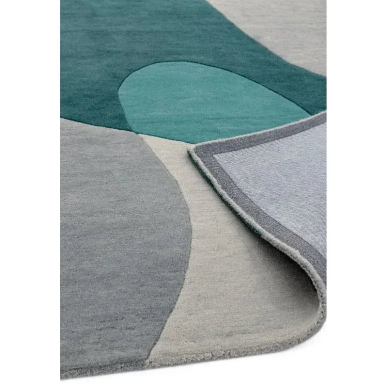 Abstract wool area rug with grey, teal and green geometric pattern, corner flipped up