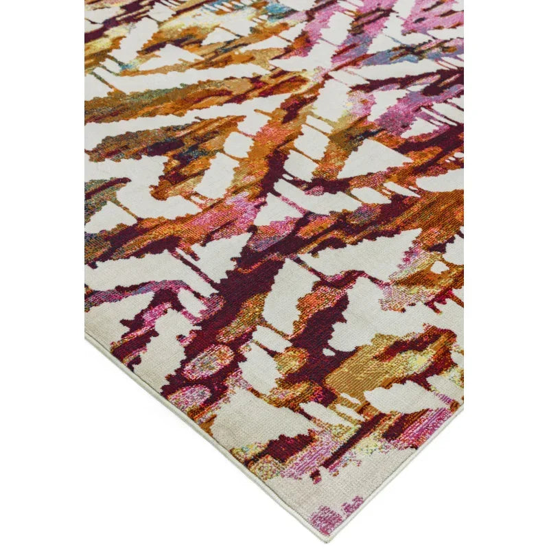 Abstract patterned area rug with orange, burgundy, and pink accents on cream background