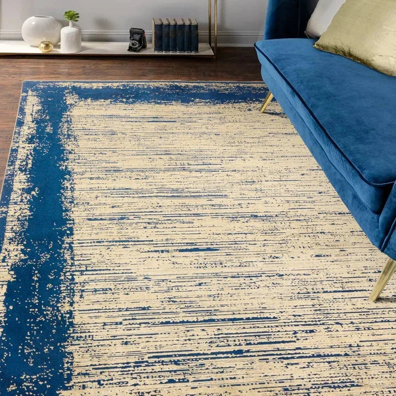 Blue and cream abstract rug with textured pattern beside blue velvet sofa on wood floor