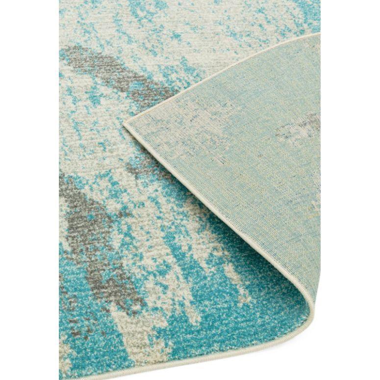 Blue and grey abstract area rug with corner flipped to show backing detail