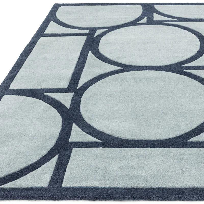 Grey geometric area rug with dark circular and linear pattern, close corner view