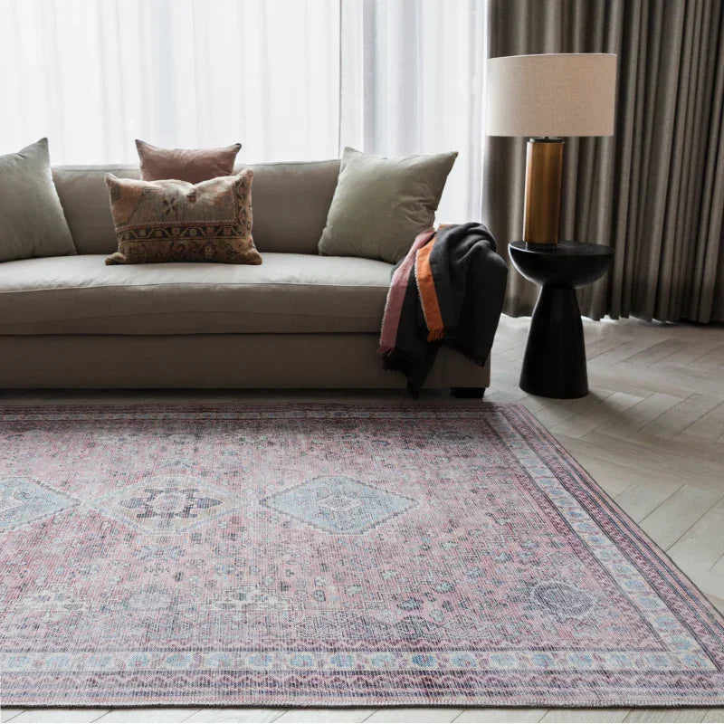 Modern beige sofa with decorative cushions and a patterned area rug in a stylish living room