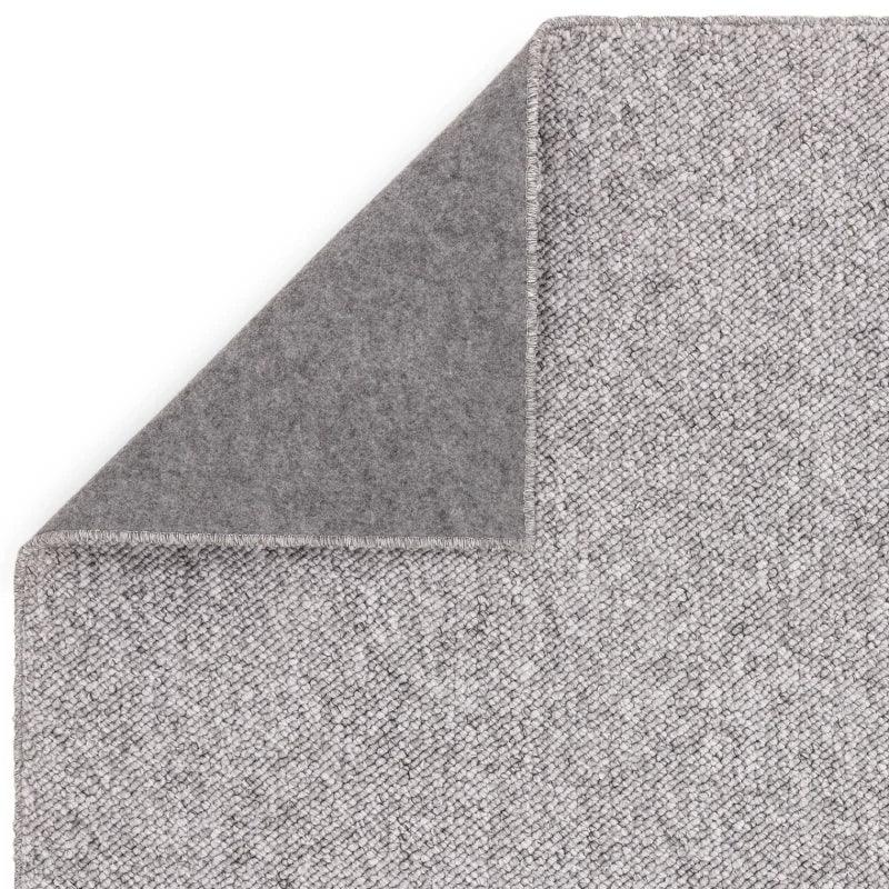Light grey textured rug with corner folded to show backing material