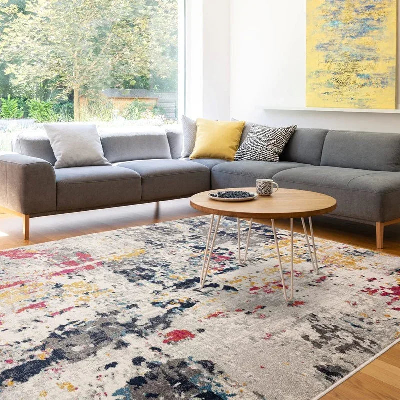 Modern grey corner sofa with scatter cushions and round coffee table on abstract area rug