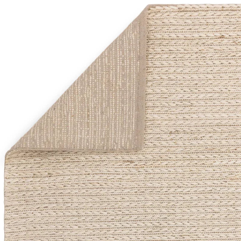 Beige jute rug closeup with textured weave and corner flipped to reveal backing