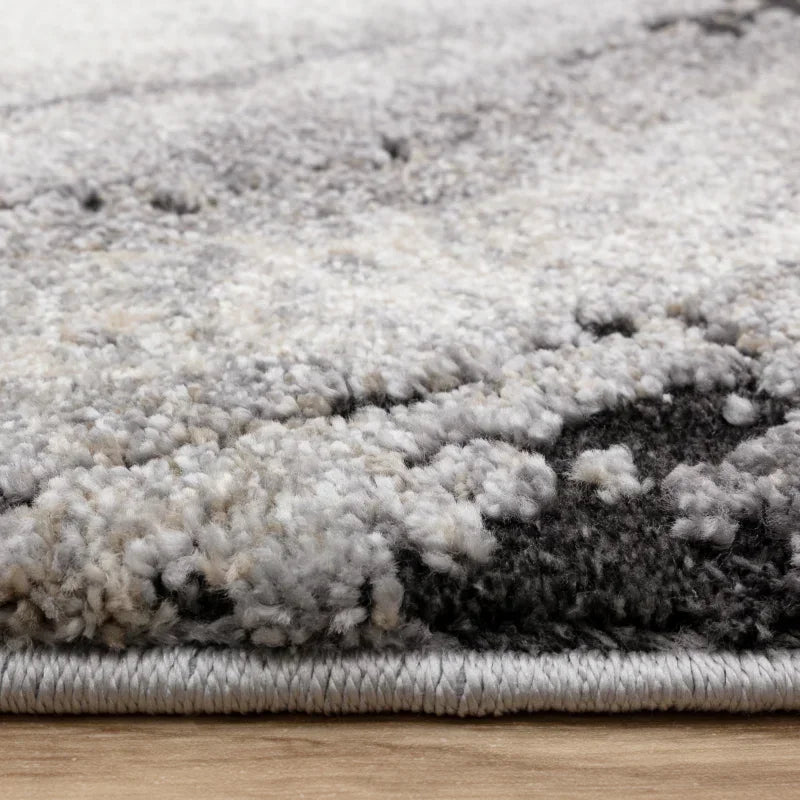 Close-up of thick grey and cream area rug pile on wooden floor