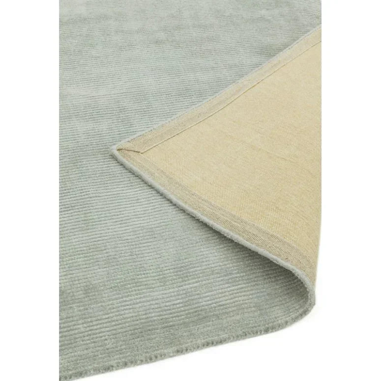 Light grey area rug with subtle ribbed texture and visible reverse showing woven backing