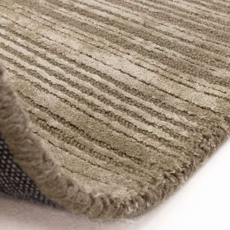 Beige textured area rug with subtle stripes and thick woven edge, close-up corner view