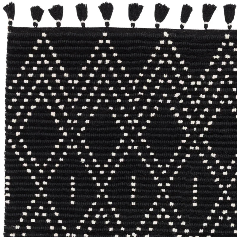 Black woven rug with white geometric pattern and tassel edge detail