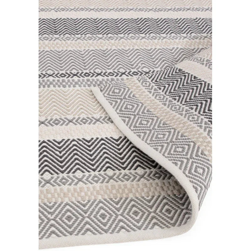 grey and cream geometric patterned rug with textured stripes and folded corner