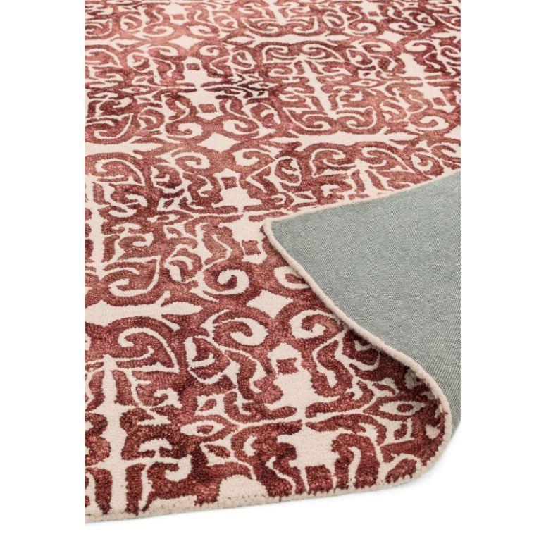 Red patterned area rug with cream background, close-up showing corner folded