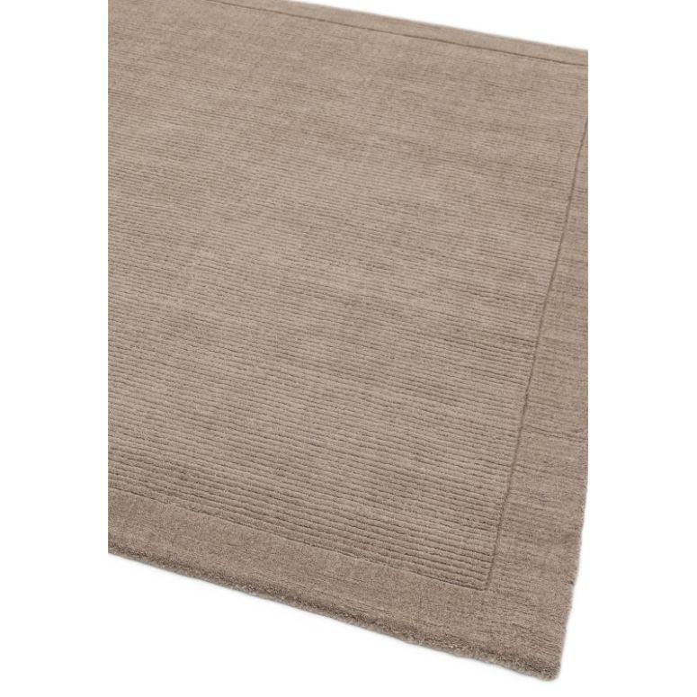 Beige textured wool rug with stitched border, corner view