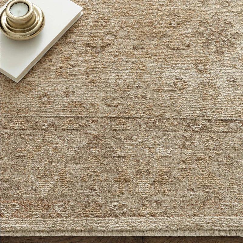 Beige textured rug with subtle patterned design and decorative tray on wooden floor