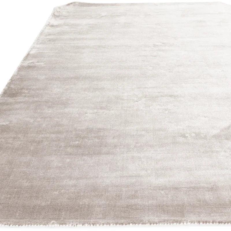Large rectangular silver area rug with short pile and soft texture, shown from corner angle