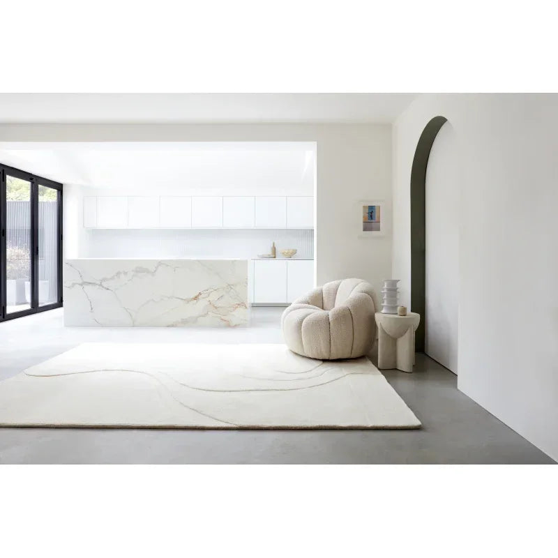 Modern cream accent chair and neutral rug in minimalist kitchen living space
