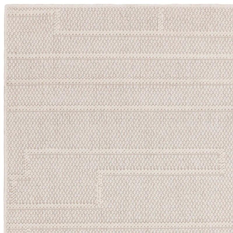 Neutral woven rug with geometric textured pattern, close-up of corner and surface detail