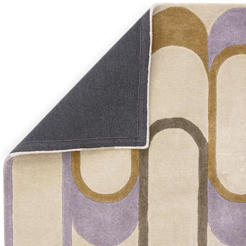Modern geometric rug with cream, gold, and lavender pattern, corner folded to show backing