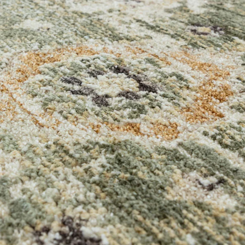 Close-up of textured area rug with green, beige, and gold abstract pattern
