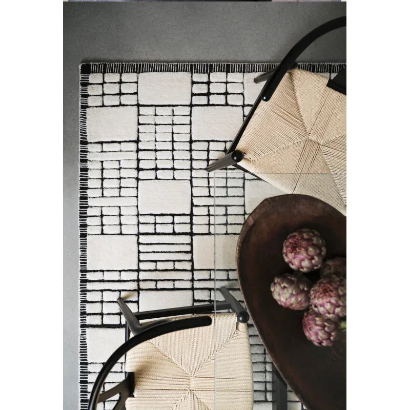 Geometric black and white area rug under modern chairs and dining table with decorative bowl