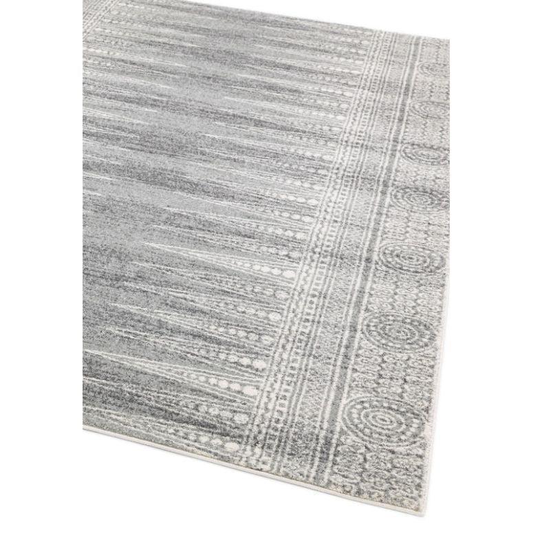 Grey patterned area rug with textured border and circular detailing, angled corner view