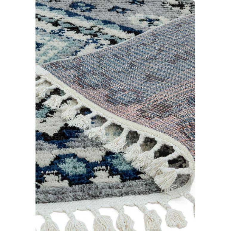 Blue and grey patterned area rug with white tassel fringe and detailed closeup corner