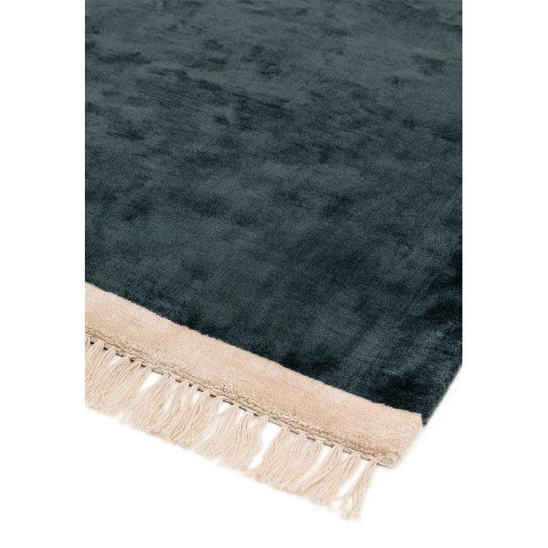 Dark green velvet rug with beige fringe detail on one edge, close-up view
