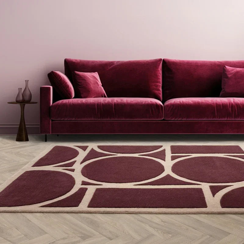 Plum velvet sofa with matching geometric rug and side table in modern living room