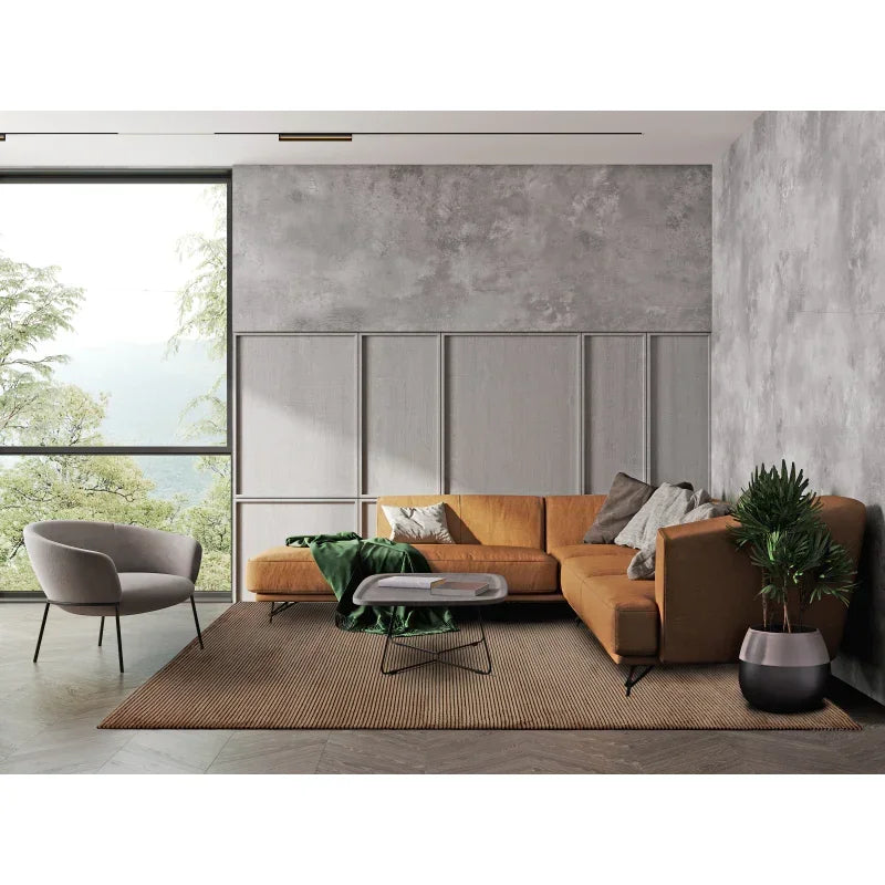 Modern living room with tan corner sofa, grey armchair, glass coffee table and indoor plant