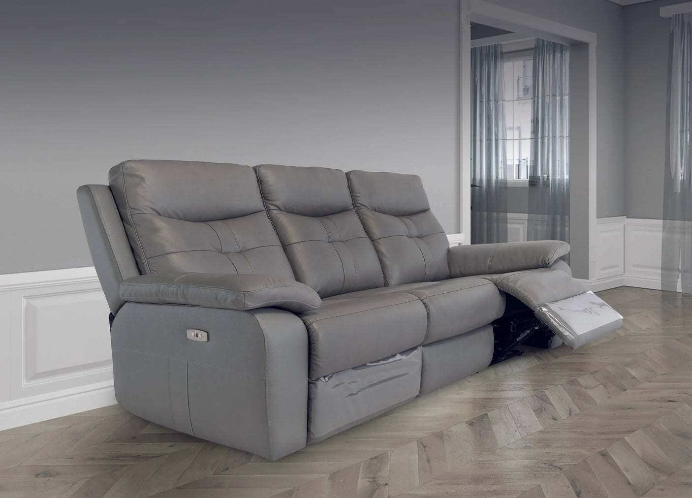 Three seater grey leather reclining sofa with padded arms and footrest extended in living room