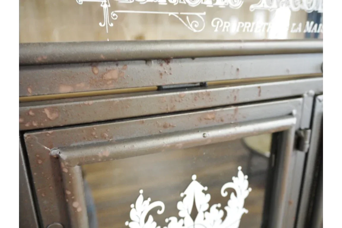 Close-up of distressed metal cabinet door with decorative glass panel and rustic finish