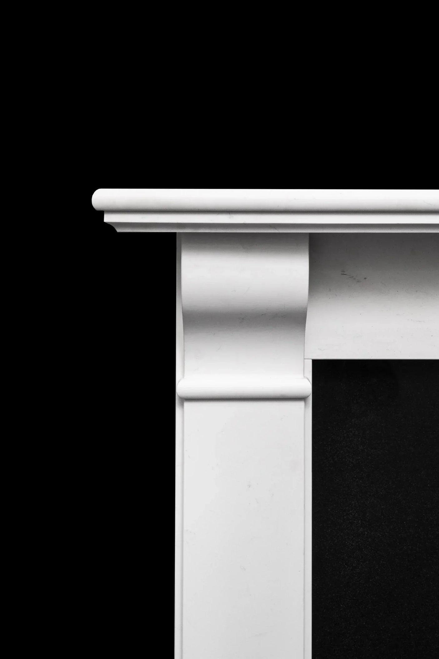 Detail of white marble fireplace surround with classic moulding against black background