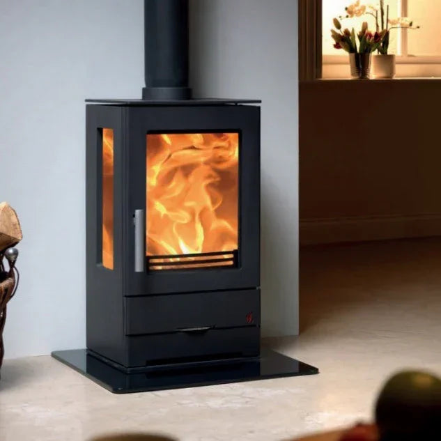 Black freestanding wood burner stove with glass sides and visible flames in living room