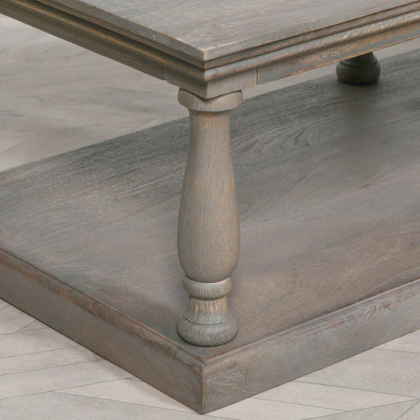 Rustic wood coffee table with turned leg and lower shelf on light herringbone floor