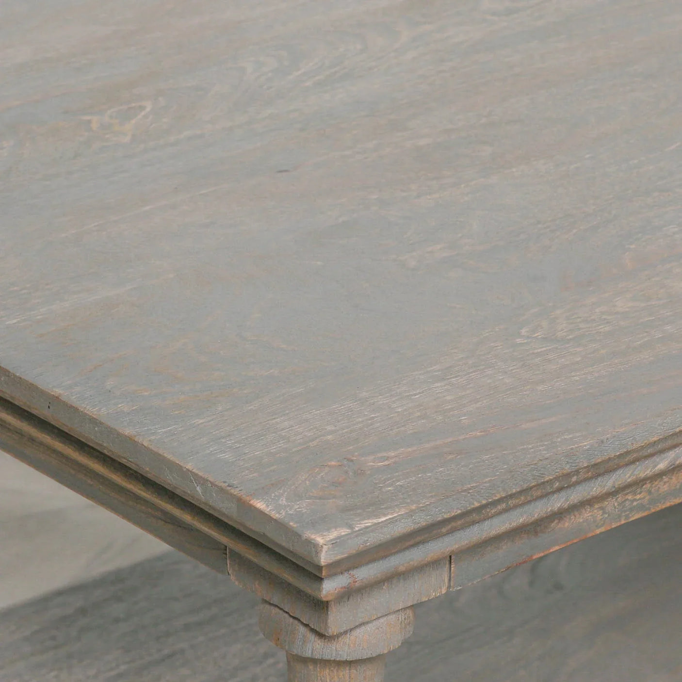 Close-up of weathered wood dining table corner with carved leg detail